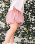Person wearing a red checkered shorts against a leafy background