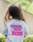 Child wearing a shirt with 'Reading is Cool' text outdoors.